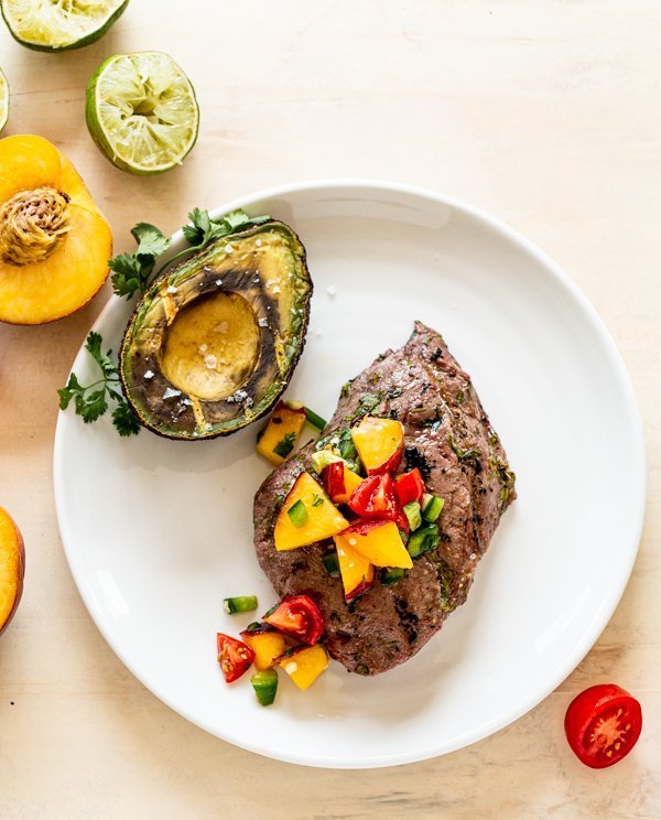 grilled elk ribeye with fresh peach salsa on a white plate