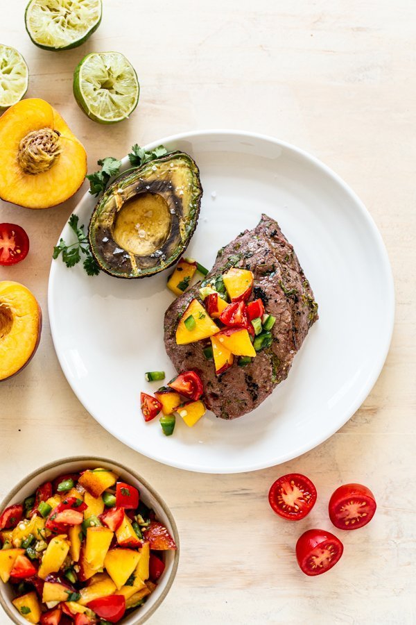 grilled avocado and grilled elk ribeye with fresh peach salsa on a white plate