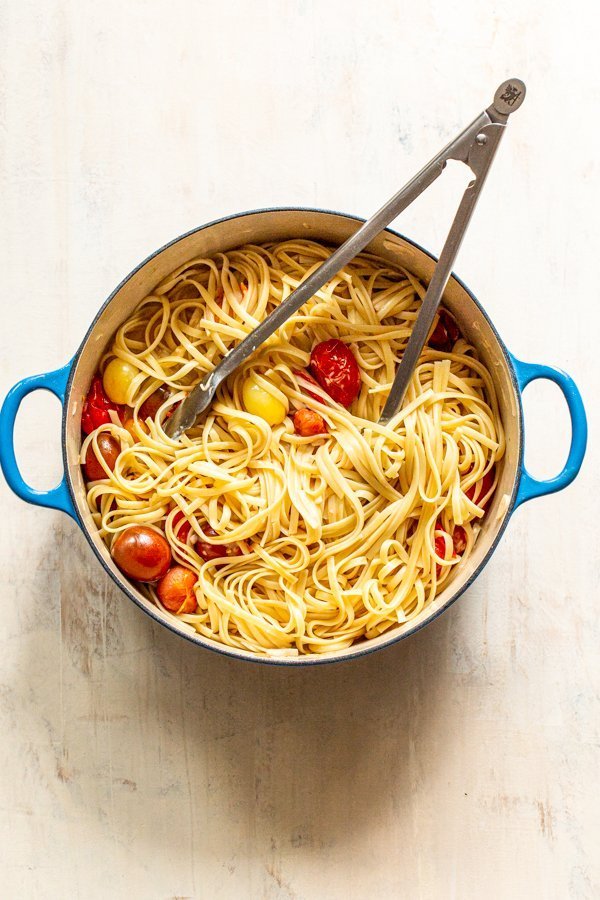 pasta in a pot being tossed with tongs