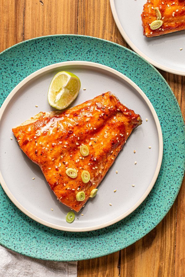 traeger smoked salmon with a sweet and spicy glaze on a blue plate and a lime