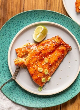 traeger smoked salmon with a sweet and spicy glaze on a blue plate and a lime