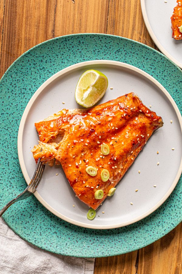 traeger smoked salmon with a sweet and spicy glaze on a blue plate and a lime