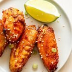 air fryer chicken wings on a cream plate with a lime