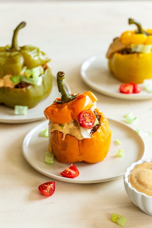 Instant pot stuffed peppers with venison and chipotle aioli on a while place with tomatoes and lettuce on top.