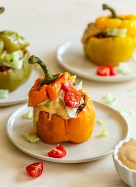 Instant pot stuffed peppers with venison and chipotle aioli on a while place with tomatoes and lettuce on top.