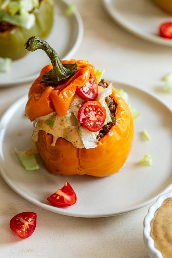 Instant pot stuffed peppers with venison and chipotle aioli on a while place with tomatoes and lettuce on top. 