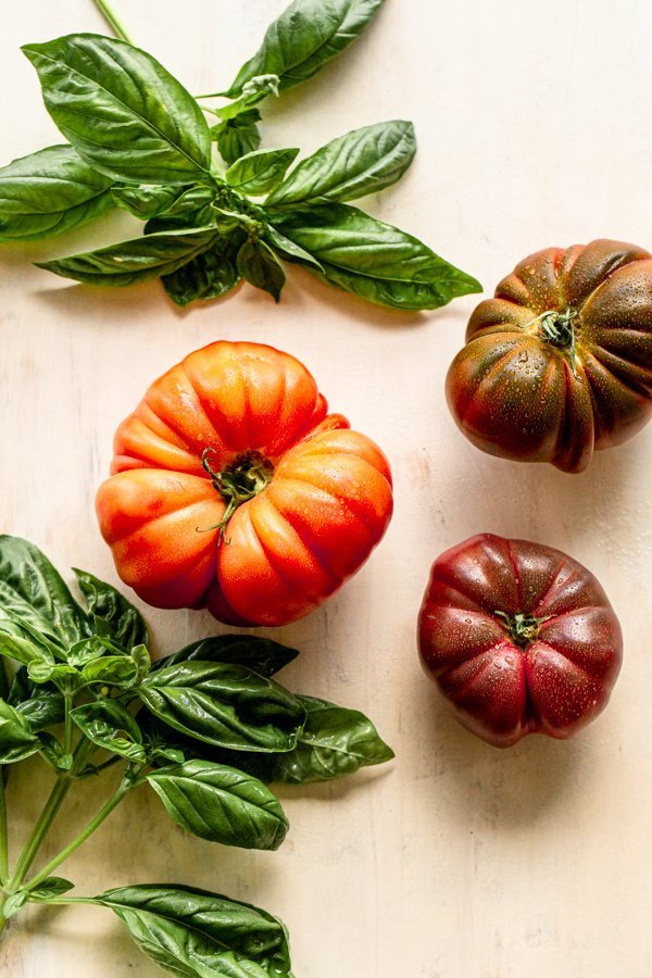 tomatoes and basil on a cream colored board