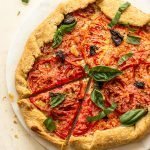 a tomato galette on a marble pastry circle with basil