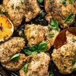 Italian baked chicken thighs in a skillet with basil