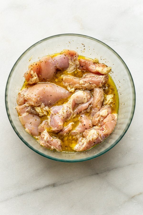 chicken marinating in a glass bowl