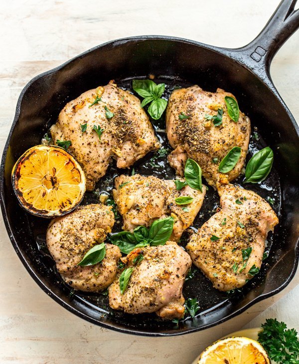 Italian baked chicken thighs in a skillet with basil