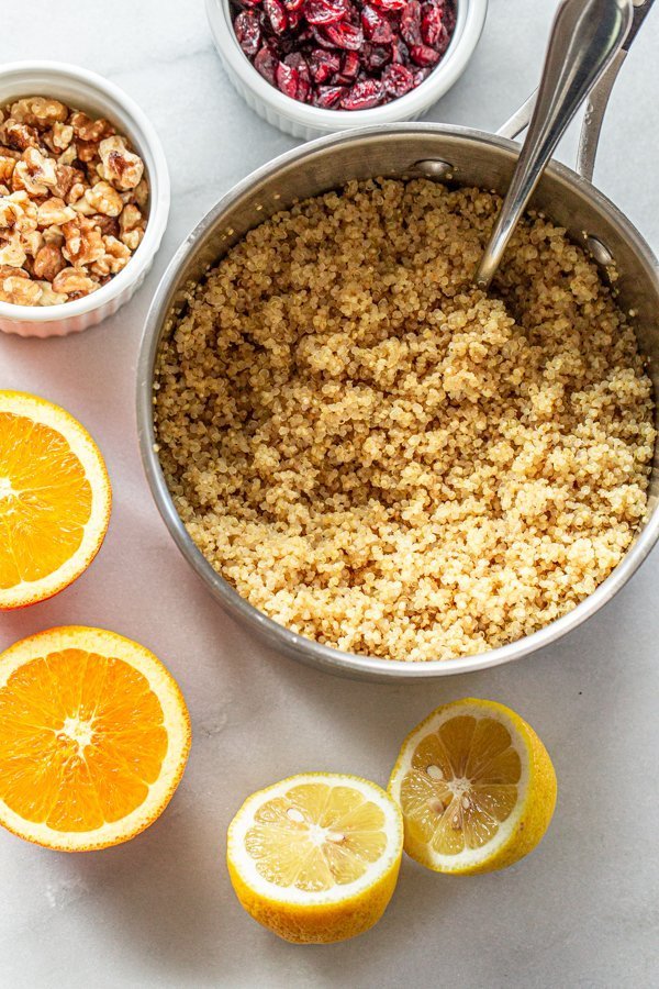 quinoa, oranges, cranberries and walnuts on a white counter