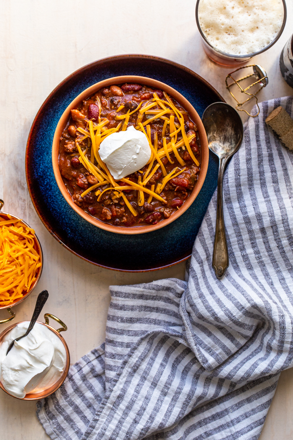 chili with cheese and sour cream in an orange bowl in a blue plate