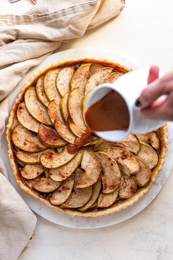 pouring caramel over an apple tart