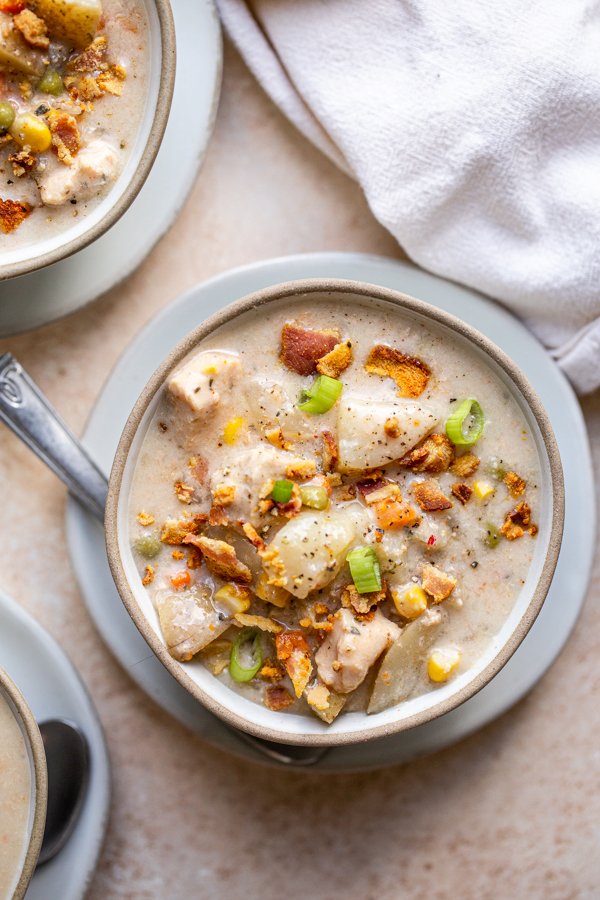 chicken corn chowder in grey bowls and a tan linen