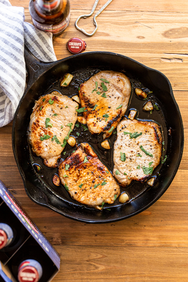 apple cider pork chops in a skillet with garlic and hard apple cider