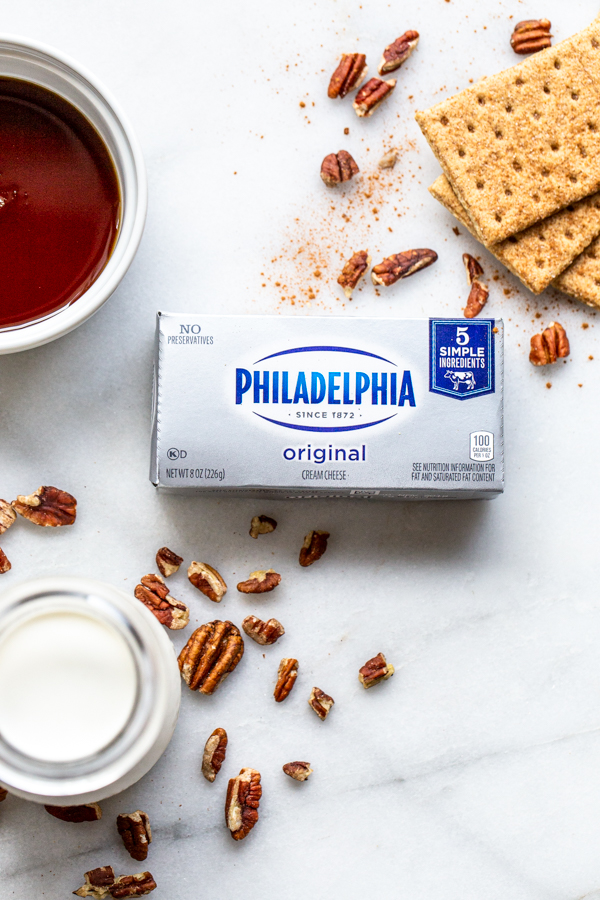 cream cheese on a marble slab with heavy cream, maple, graham crackers and pecans