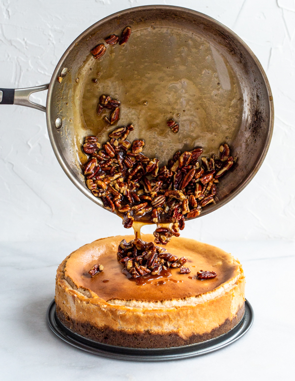 Pecan pie filling being poured over cheesecake