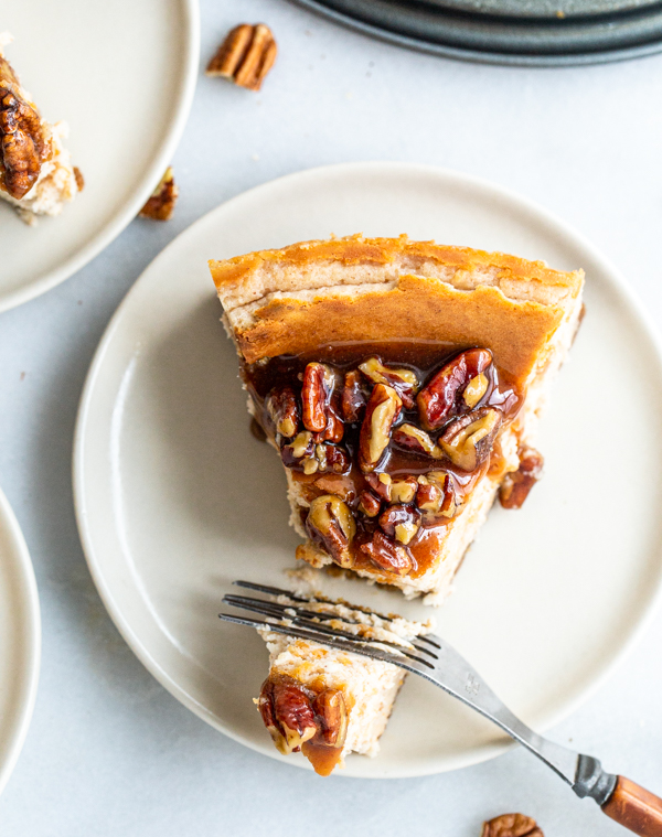 Pecan Pie Cheesecake slice on a white plate with a fork cutting it