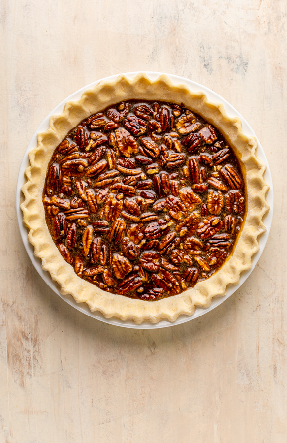 unbaked pecan pie on a cream counter