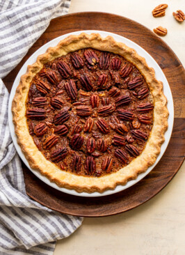 pecan pie in a white pie dish on a wood slab