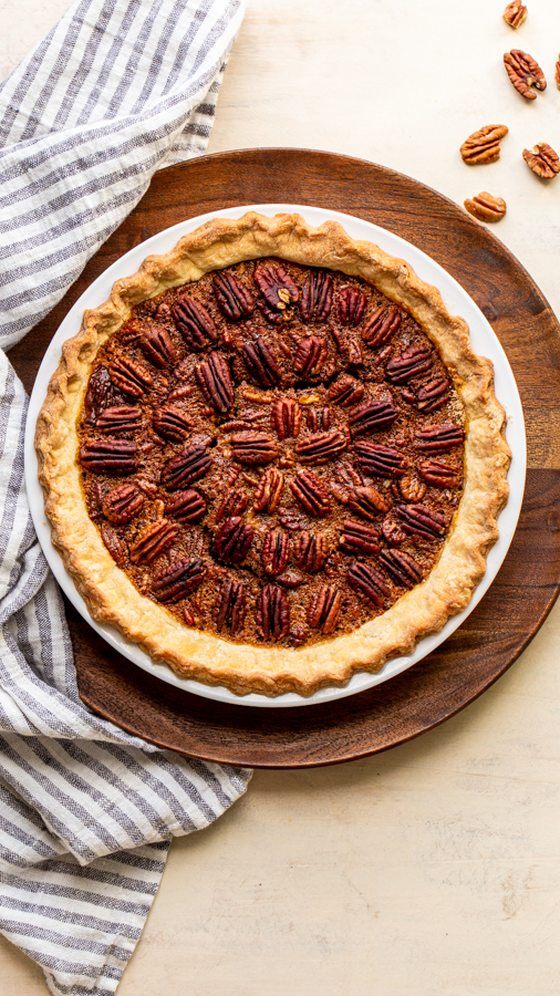 pecan pie in a white pie dish on a wood slab