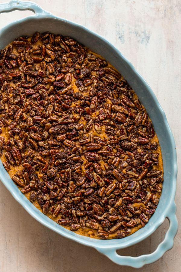 pecans covering whipped sweet potatoes in a blue oval casserole dish