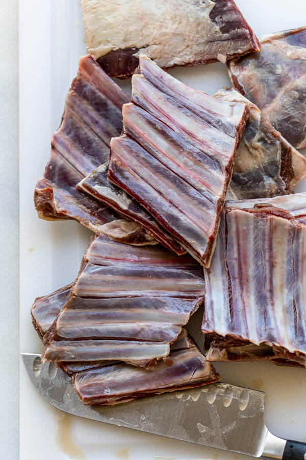 raw short ribs from a deer on a white cutting board