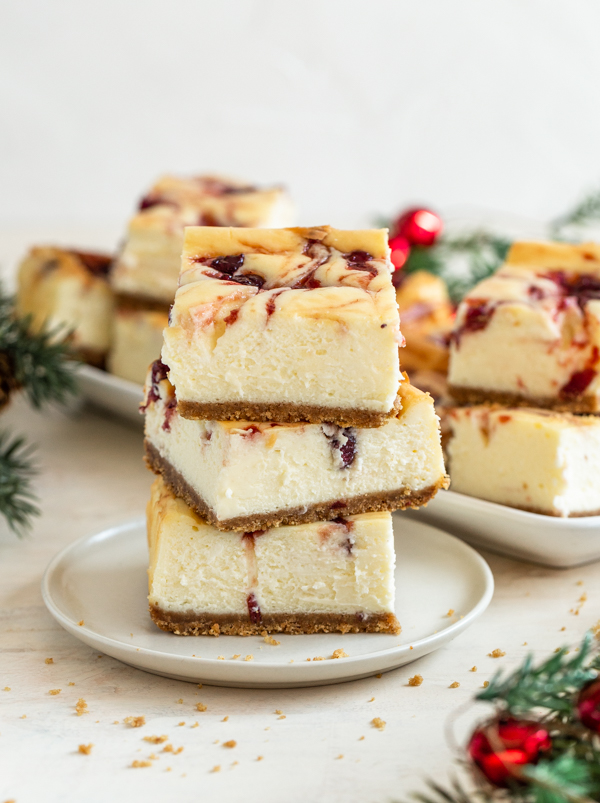 stacked cranberry cheesecake bars on a white plate