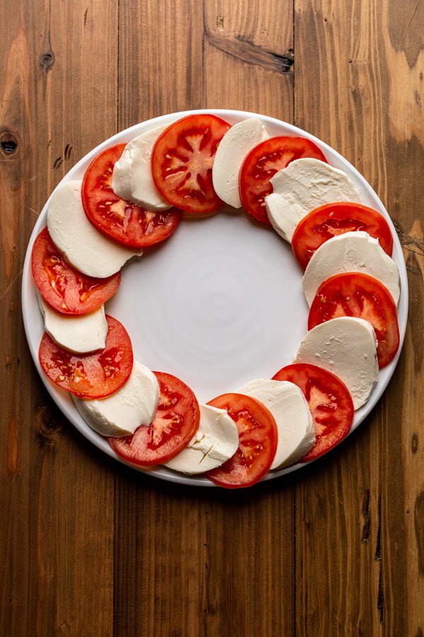 tomatoes and cheese arranged in a circle on a white plate