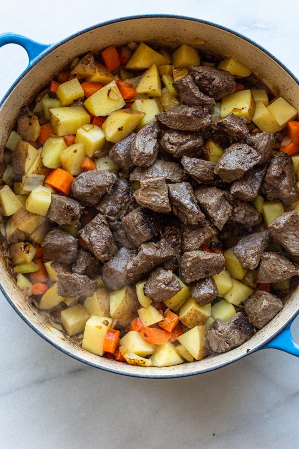 venison on top of a pot of vegetables