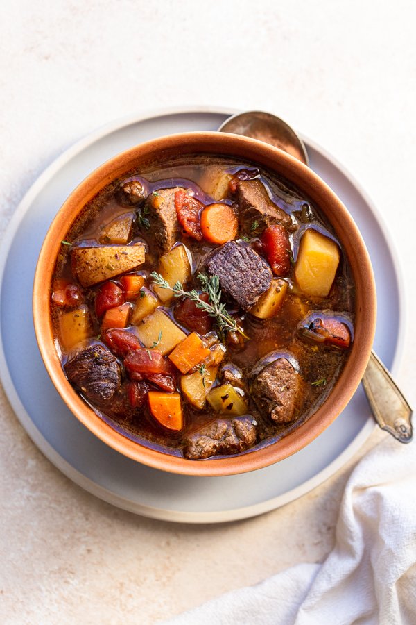 venison stew in a terra-cotta bowl with a thyme leaf