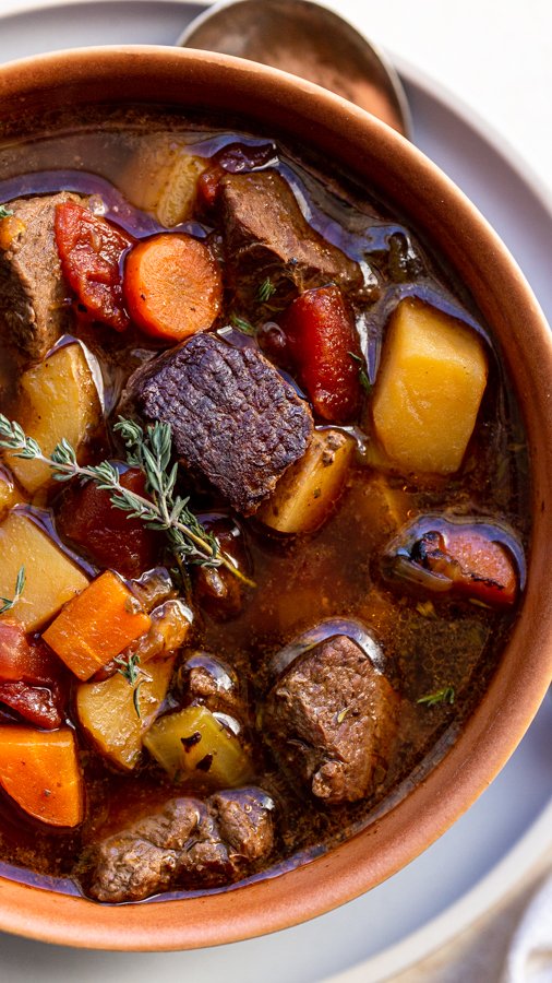 venison stew in a terra-cotta bowl with a thyme leaf