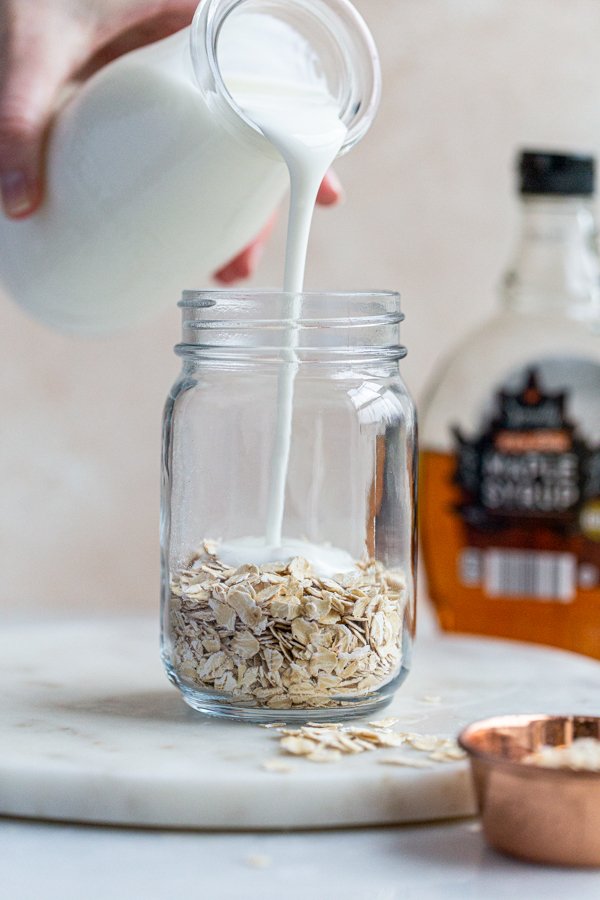kefir milk being poured over oats in a glass jar