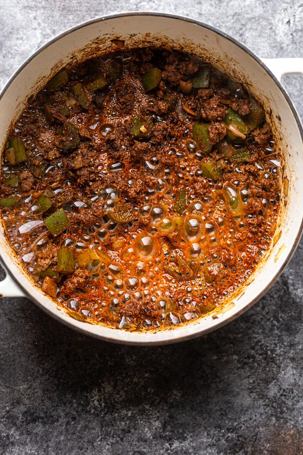 beer poured into a pot over veggies and ground meat