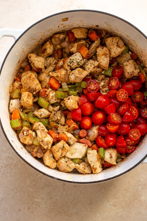 tomatoes, chicken, carrots, and celery in a pot