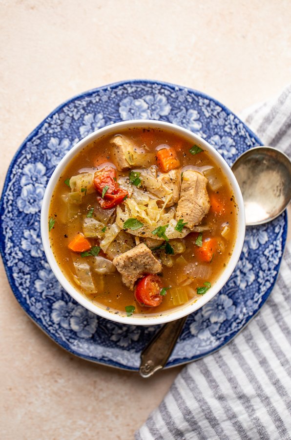 chicken and vegetable soup on a blue and white plate