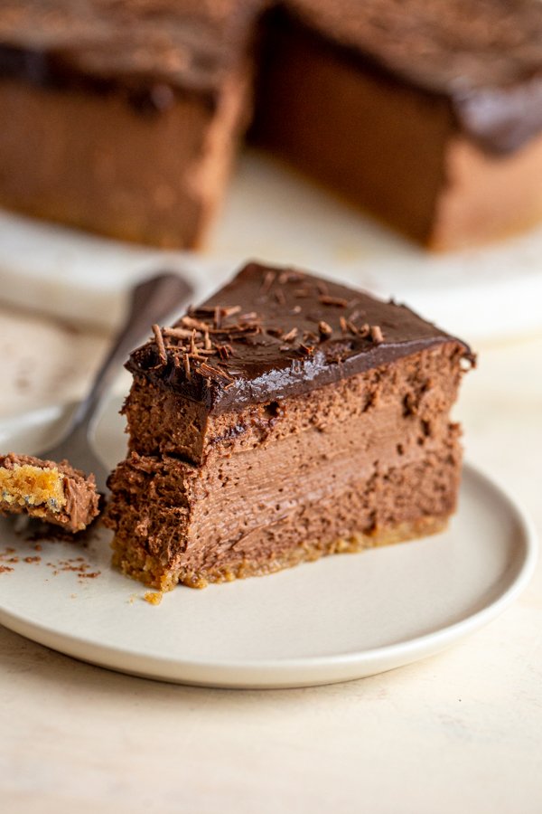 a slice of chocolate cheesecake on a white plate with a bite out of it