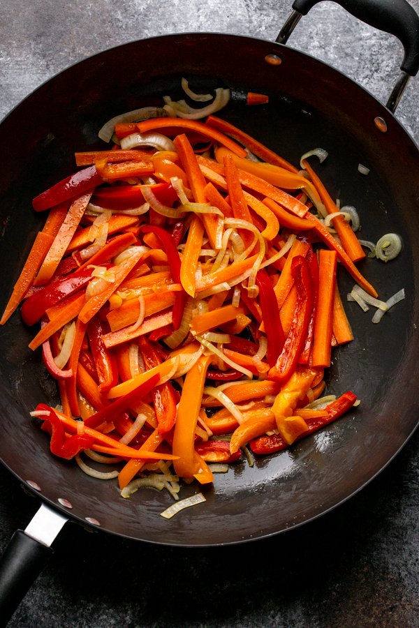 peppers, onions and carrots in a wok