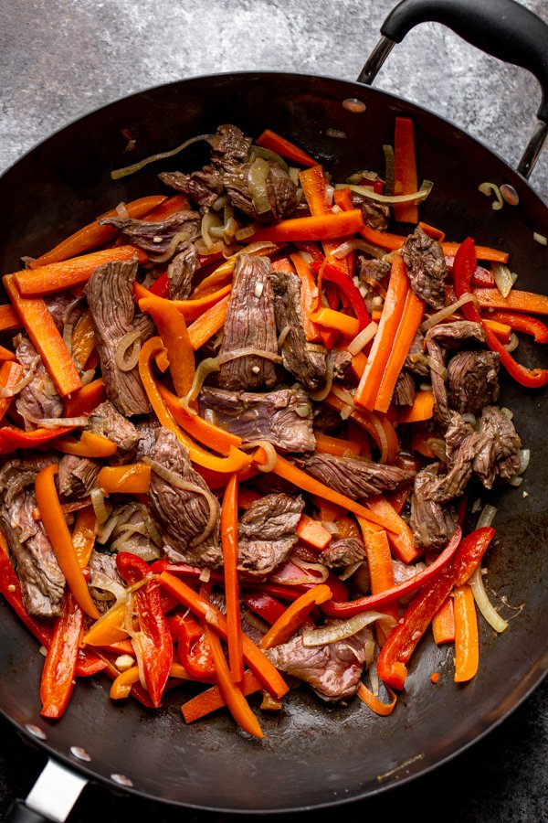 peppers, onions, carrots and venison steak in a wok