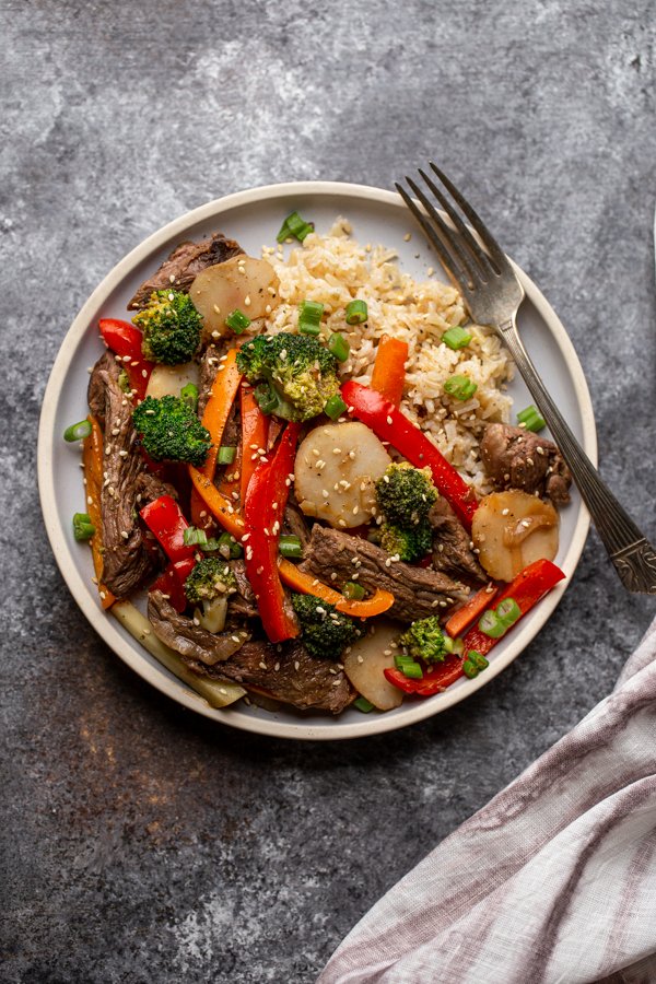 venison stir fry on a light blue plate with a fork