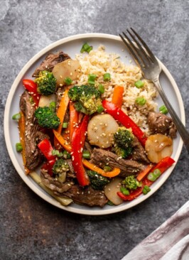 venison stir fry on a light blue plate with a fork