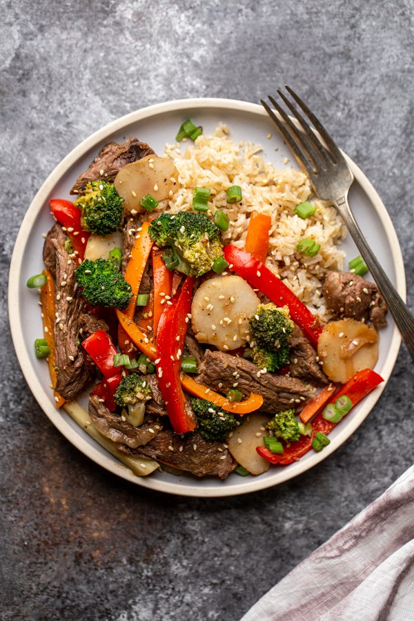 venison stir fry on a light blue plate with a fork