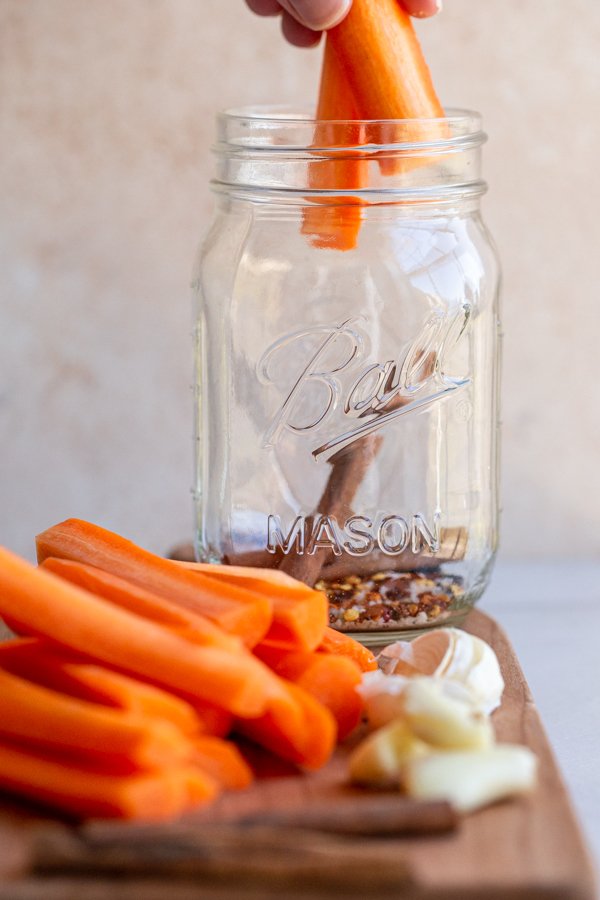 placing carrots in a glass jar