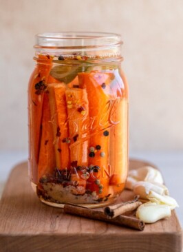 spicy fermented carrots in a glass jar with garlic and cinnamon sticks