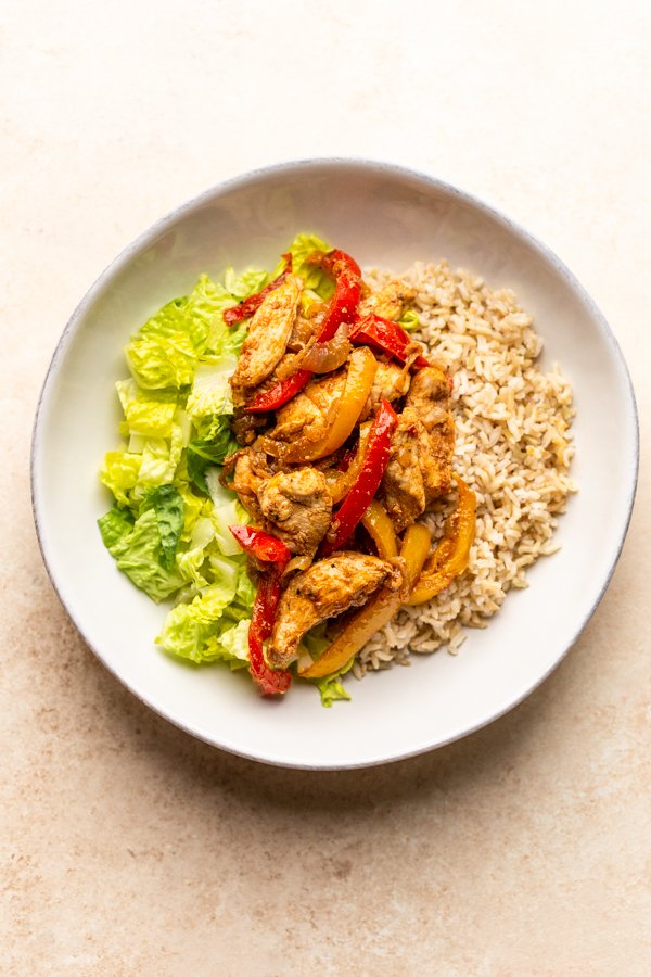 lettuce, chicken, peppers, onions and rice in a white bowl