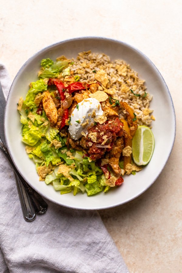 chicken fajita bowl with sour cream in a white bowl