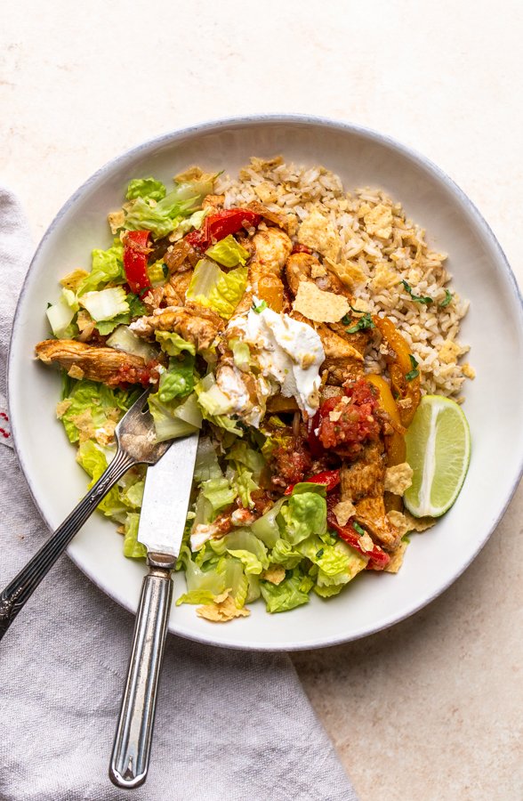 chicken fajita bowl with sour cream in a white bowl