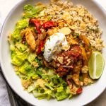 chicken fajita bowl with sour cream in a white bowl