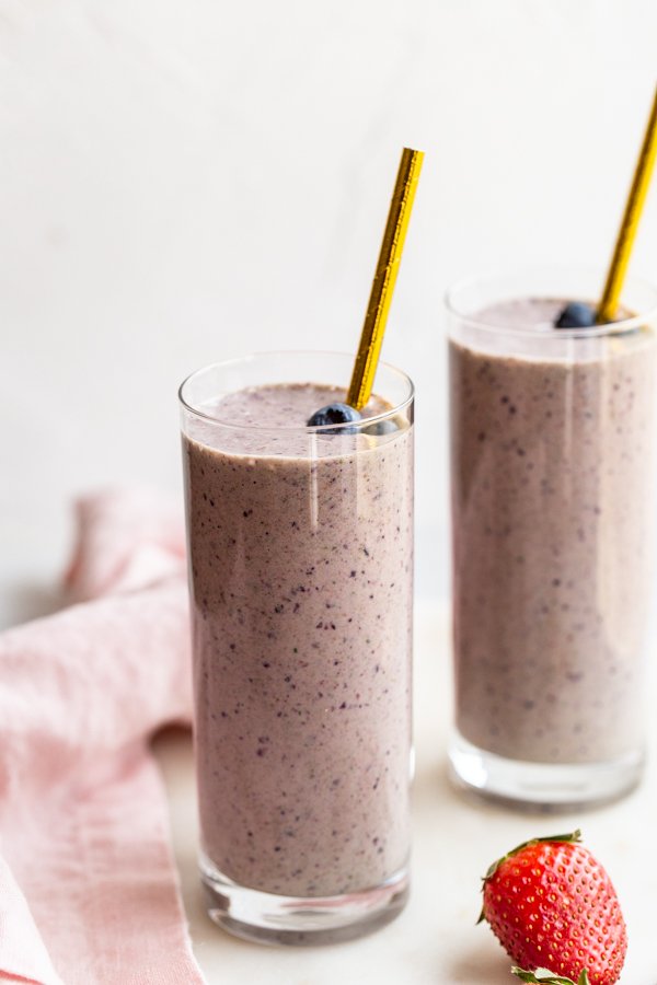 kefir smoothie glasses with a pink linen and strawberry on a marble counter